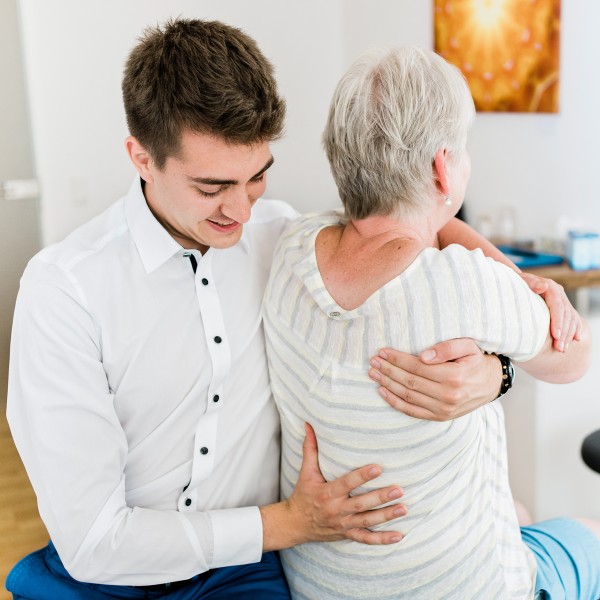 Osteopathische Behandlung am oberen Rücken einer Kundin