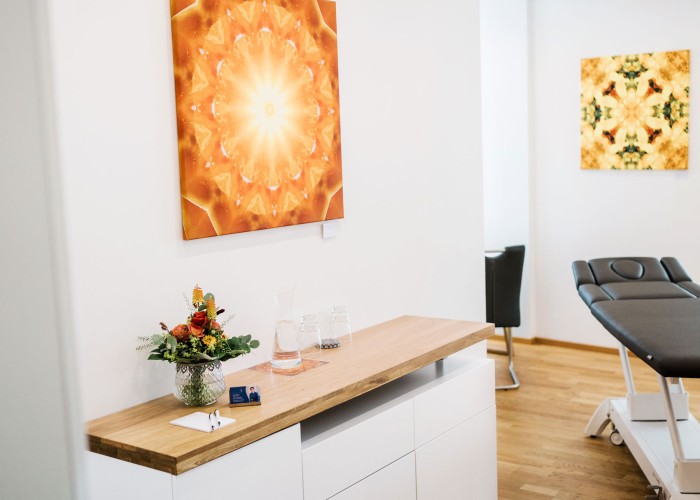 Behandlungsraum mit Liege und warmem Wandbild